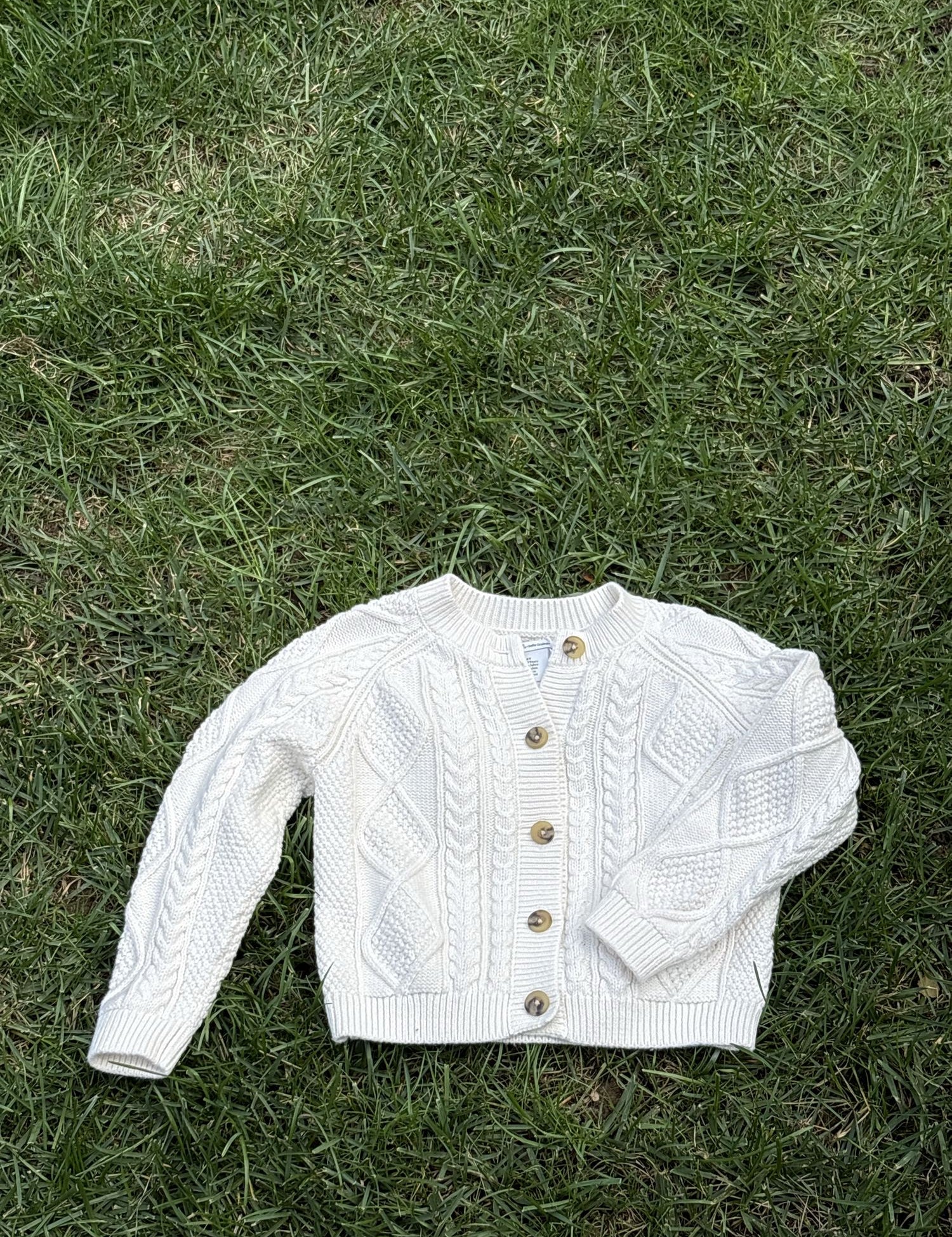 Pre-loved Amazon Essentials sofia grainge cream cable-knit cardigan, kids size 4T, front view, laid flat on grass