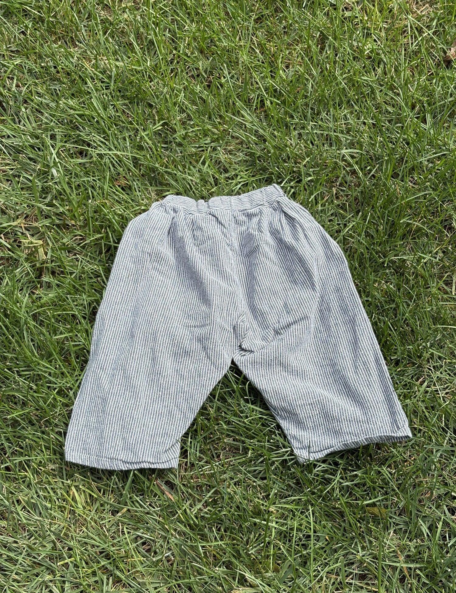 Pre-loved Aosta blue hickory stripe pull-on pants, kids size 2T, front view, laid flat on grass