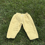 Pre-loved Aosta butter yellow cotton gauze pull-on pants, kids size 2T, back view, laid flat on grass