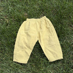 Pre-loved Aosta butter yellow cotton gauze pull-on pants, kids size 2T, front view, laid flat on grass