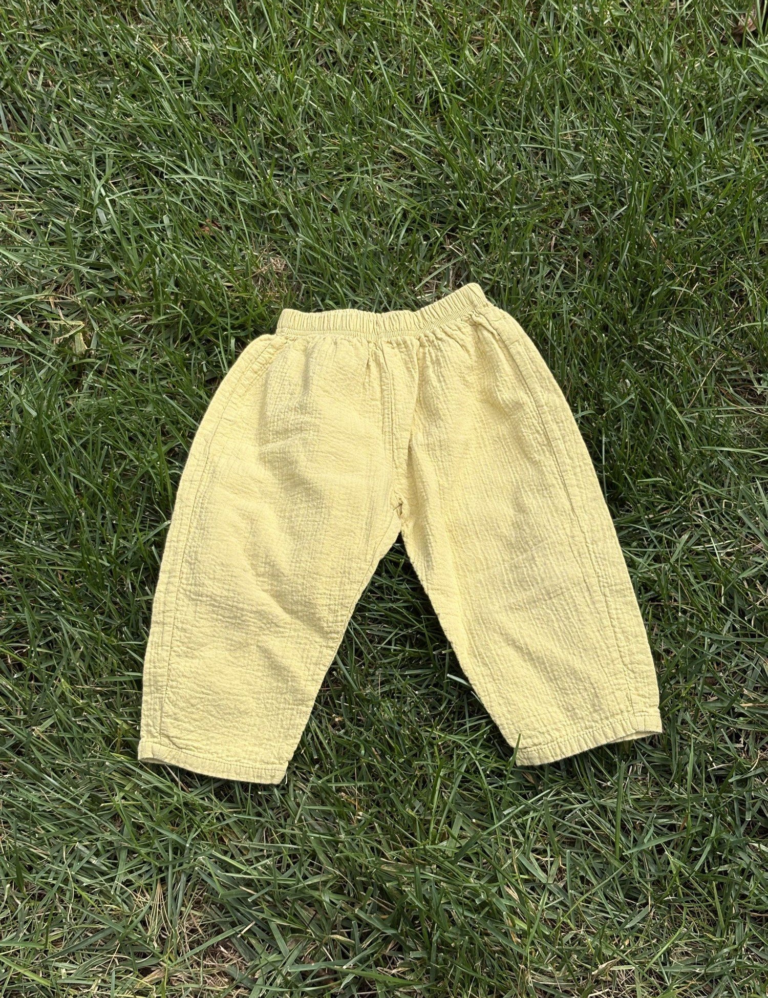 Pre-loved Aosta butter yellow cotton gauze pull-on pants, kids size 2T, front view, laid flat on grass