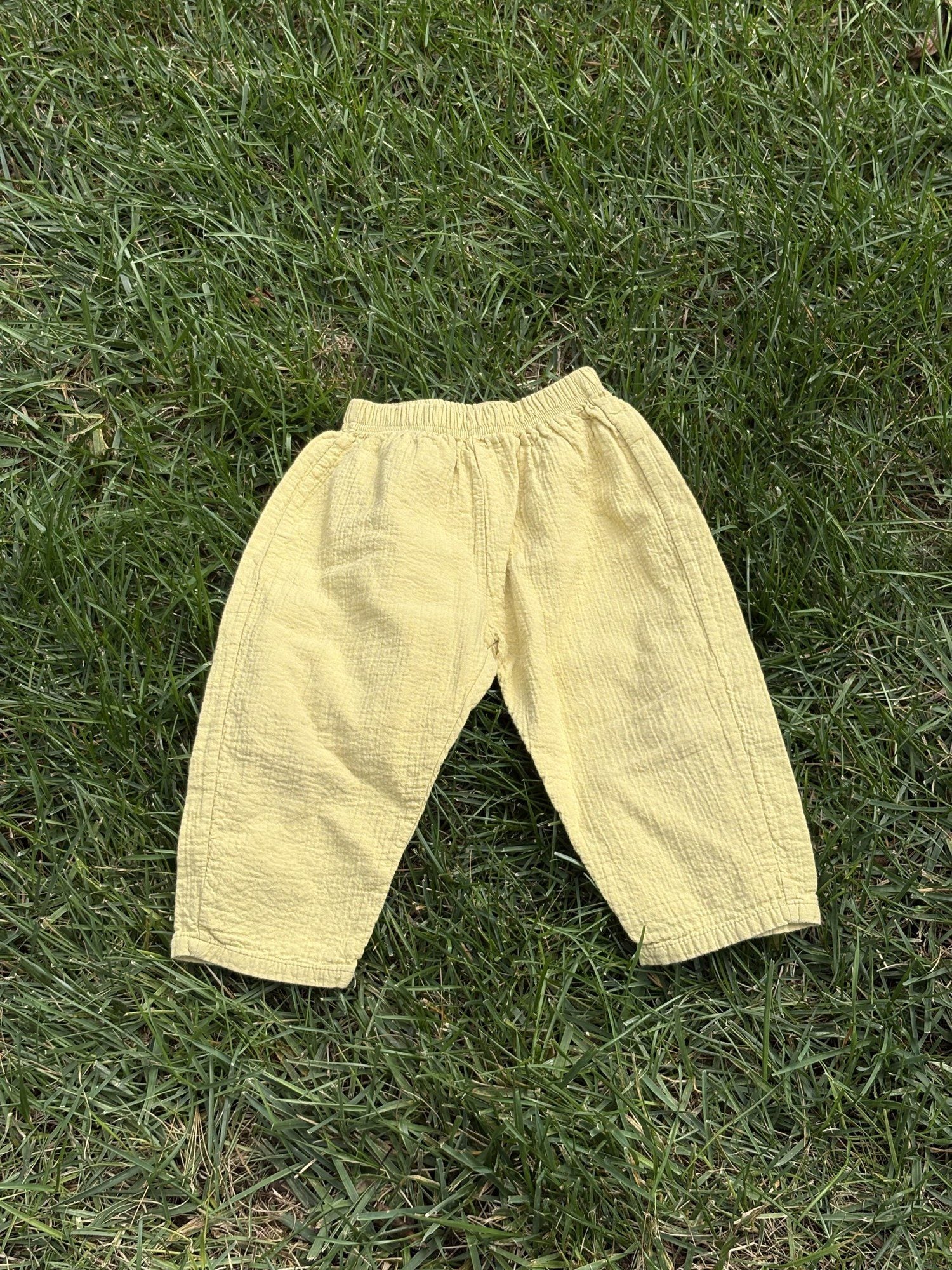 Pre-loved Aosta butter yellow cotton gauze pull-on pants, kids size 2T, front view, laid flat on grass