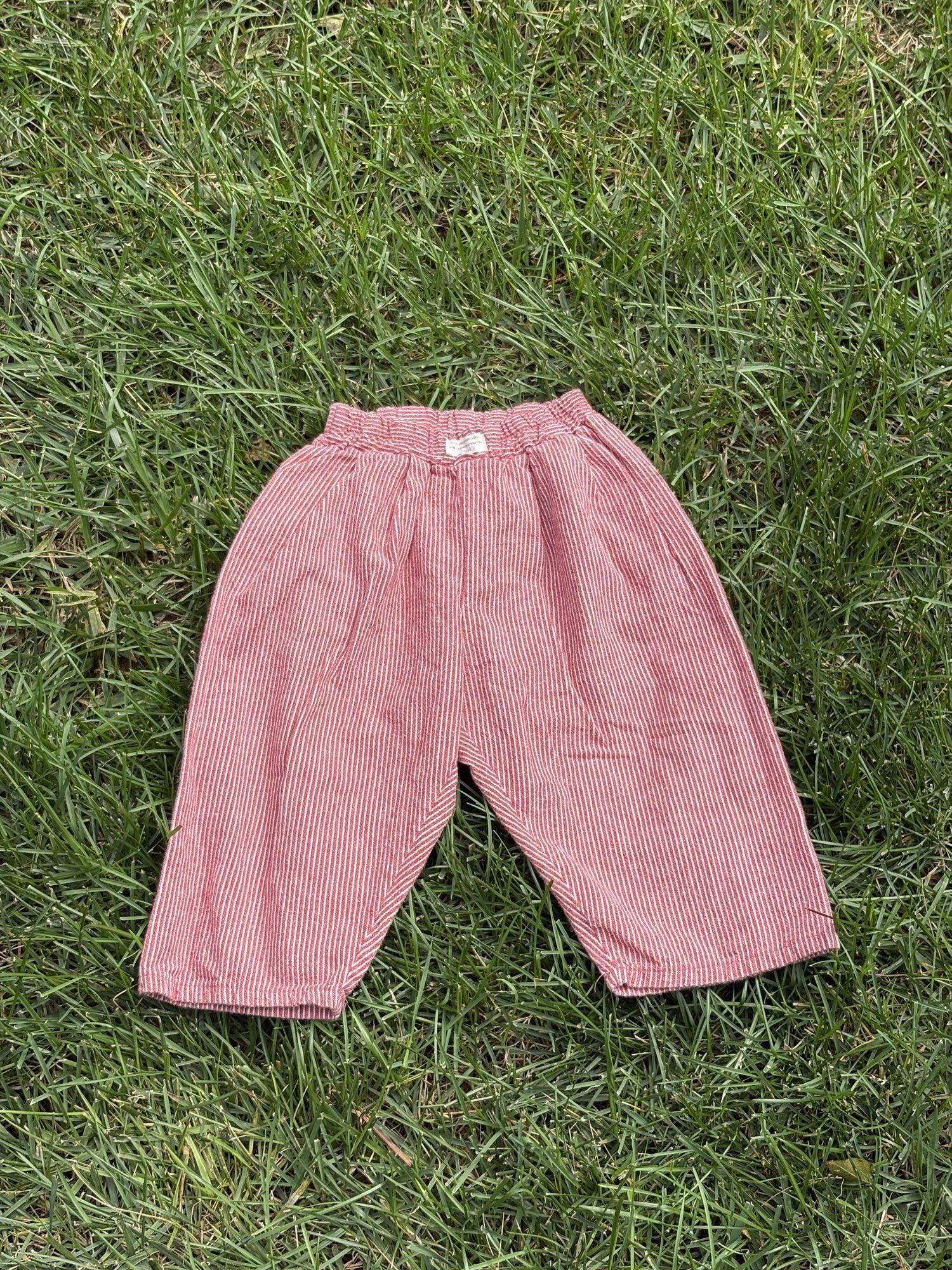 Pre-loved Aosta red hickory stripe pull-on pants, kids size 2T, back view, laid flat on grass