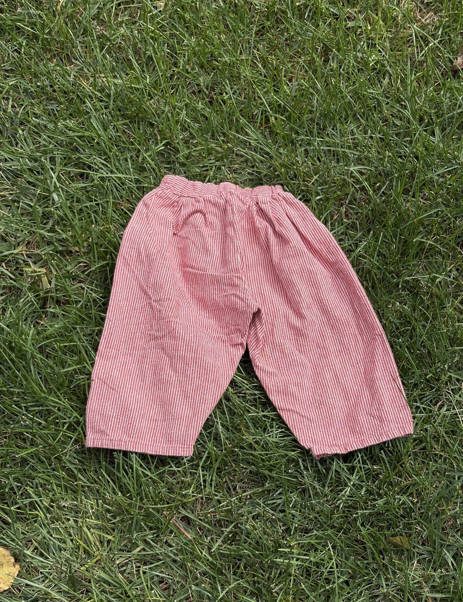 Pre-loved Aosta red hickory stripe pull-on pants, kids size 2T, front view, laid flat on grass