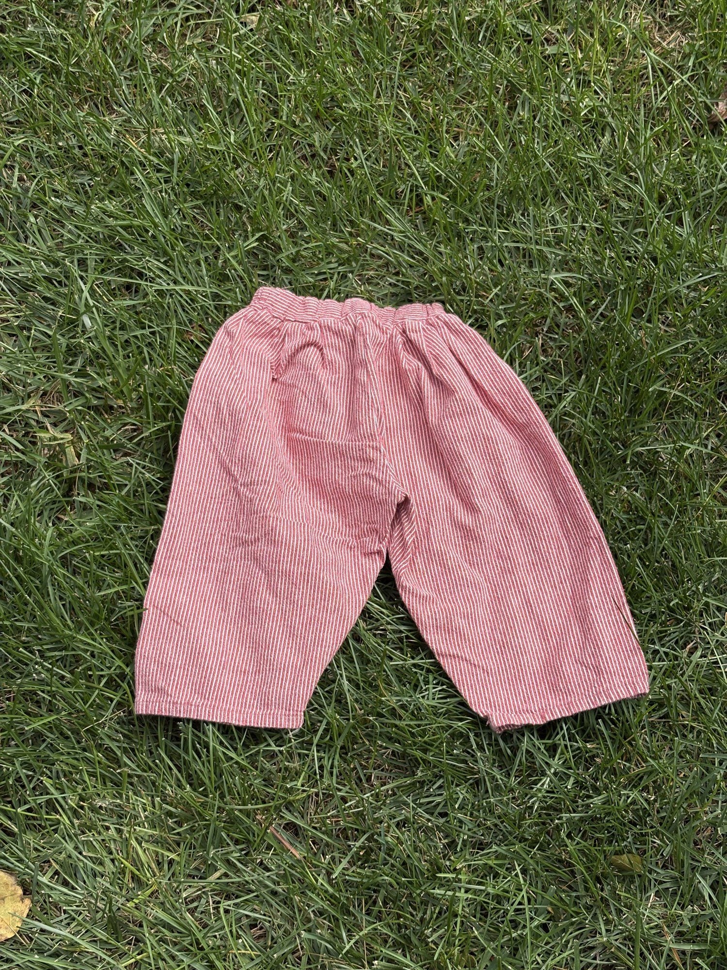 Pre-loved Aosta red hickory stripe pull-on pants, kids size 2T, front view, laid flat on grass