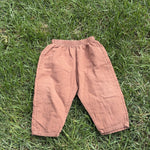 Pre-loved Aosta rust cotton gauze pull-on pants, kids size 2T, front view, laid flat on grass