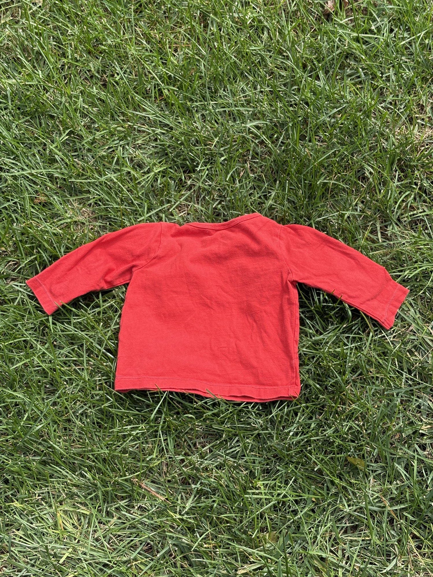 Pre-loved Boden red train graphic long-sleeve tee, kids size 6-12M, back view, laid flat on grass