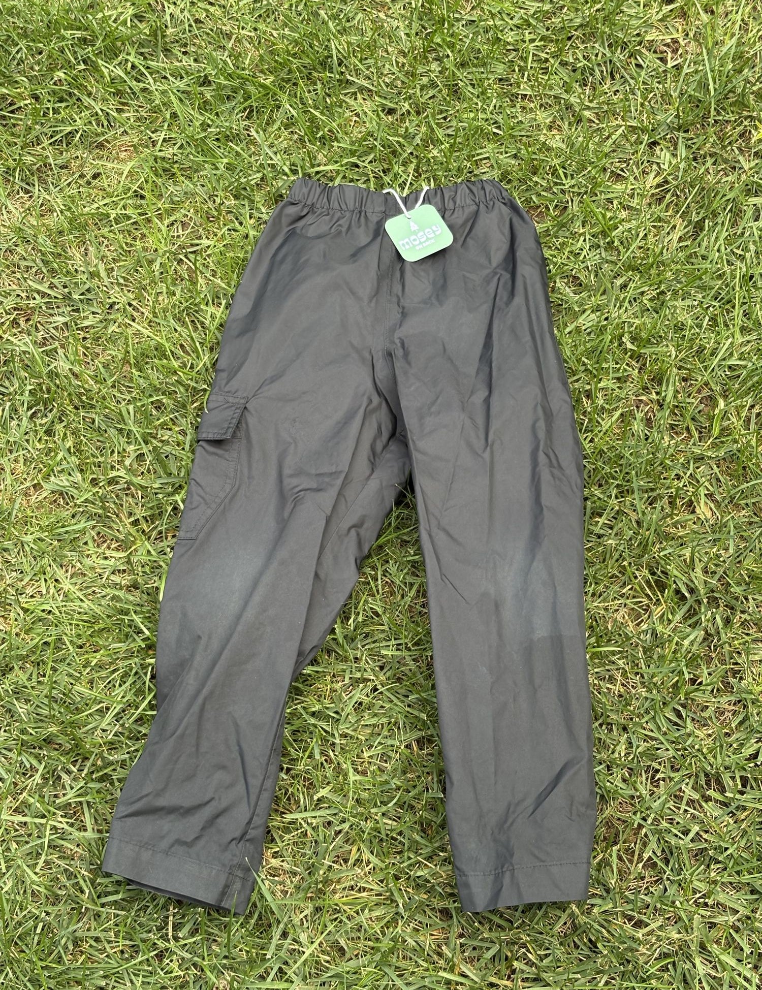 Pre-loved Columbia black pull-on rain pants, kids size 4/5, front view, laid flat on grass