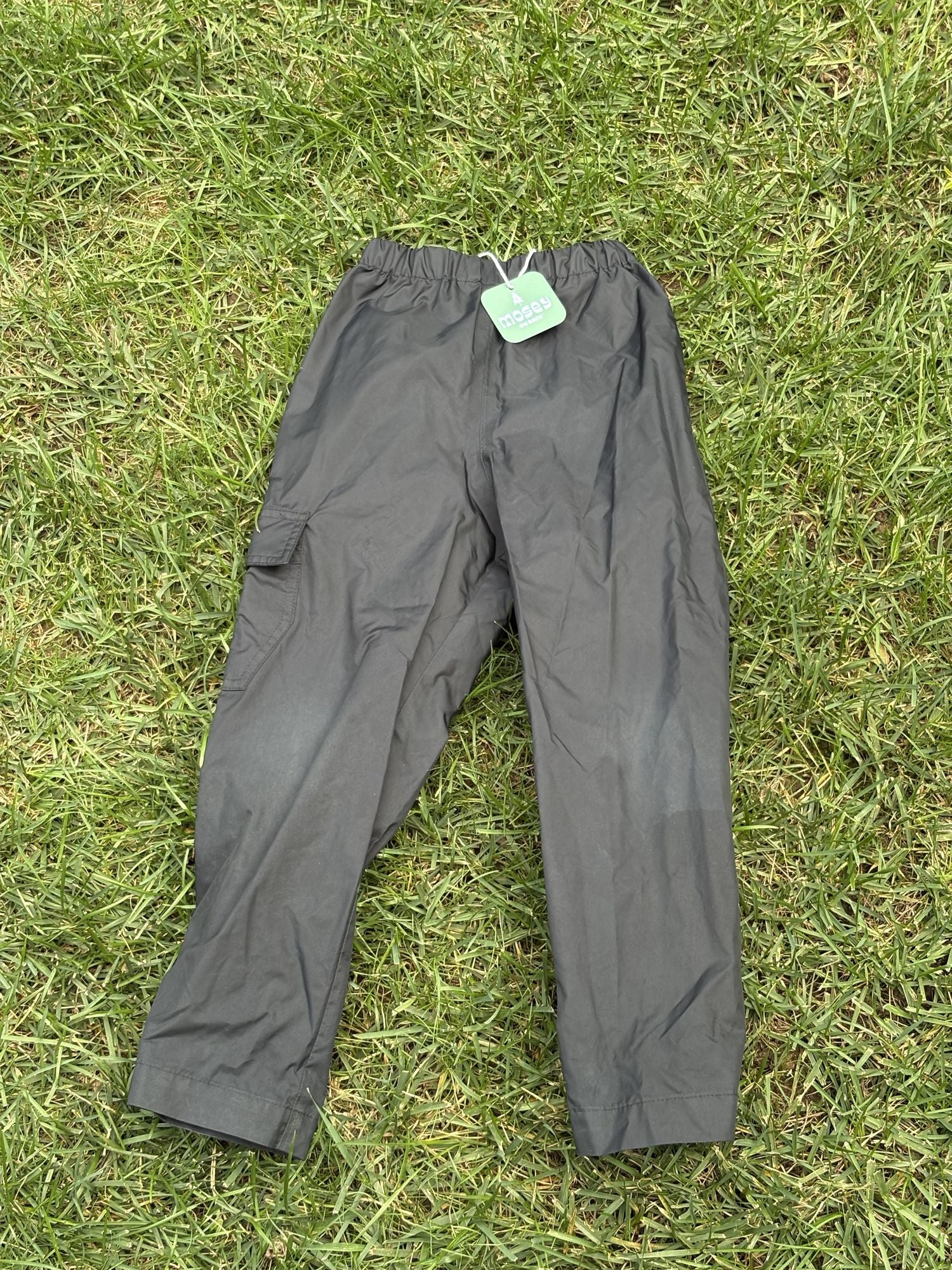 Pre-loved Columbia black pull-on rain pants, kids size 4/5, front view, laid flat on grass