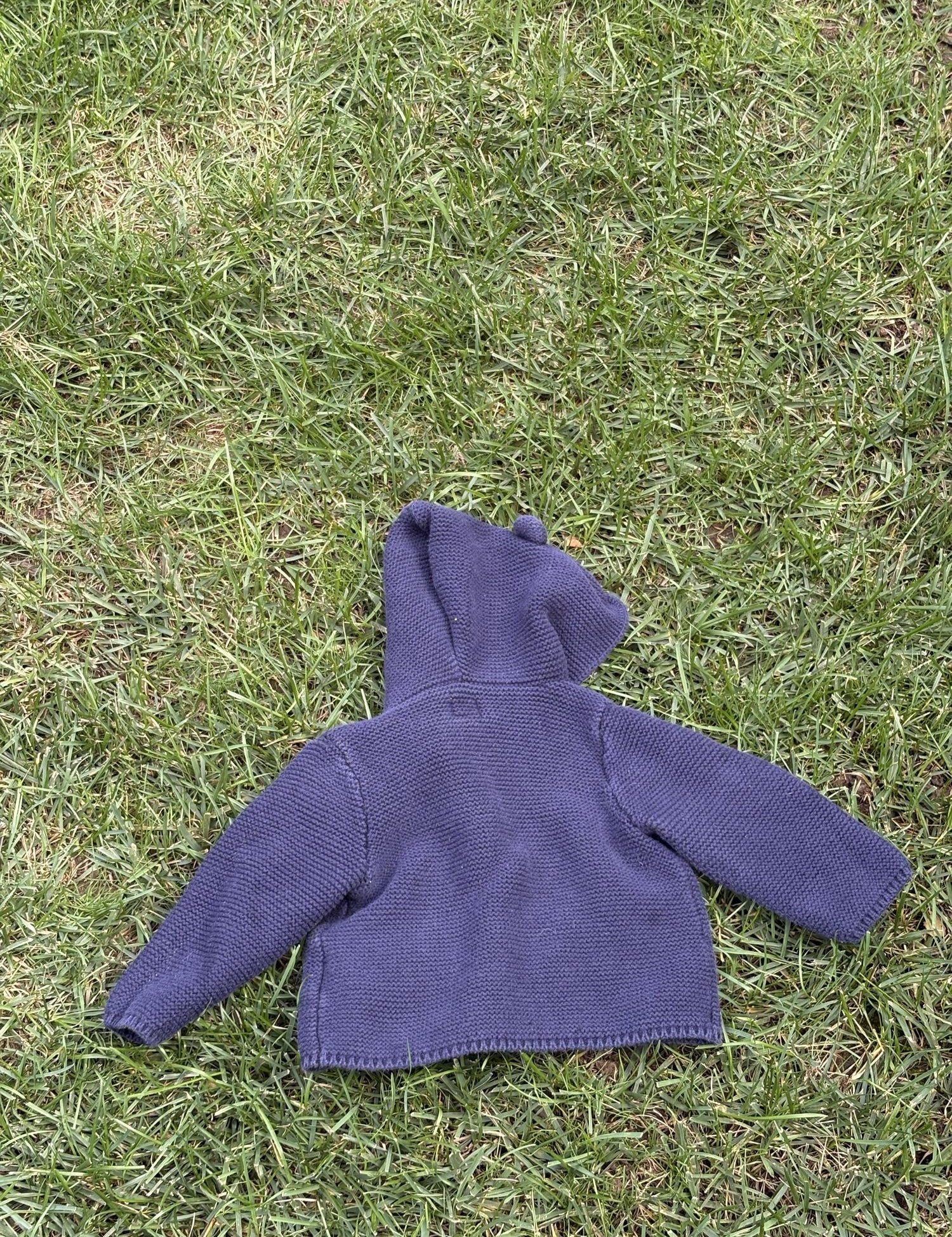 Pre-loved Gap navy bear-ear hooded knit cardigan, kids size 6-12M, back view, laid flat on grass