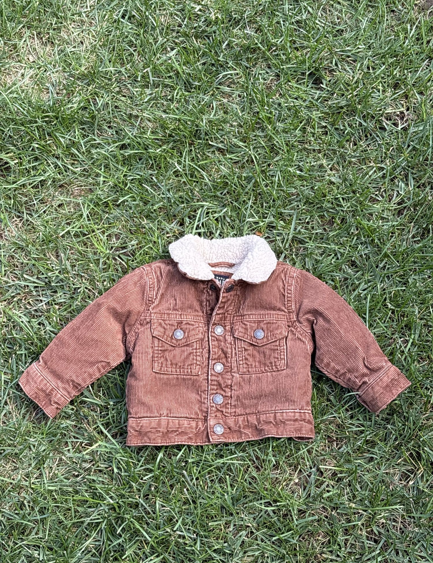Pre-loved Gap rust corduroy sherpa-collar trucker jacket, kids size 6-12M, front view, laid flat on grass