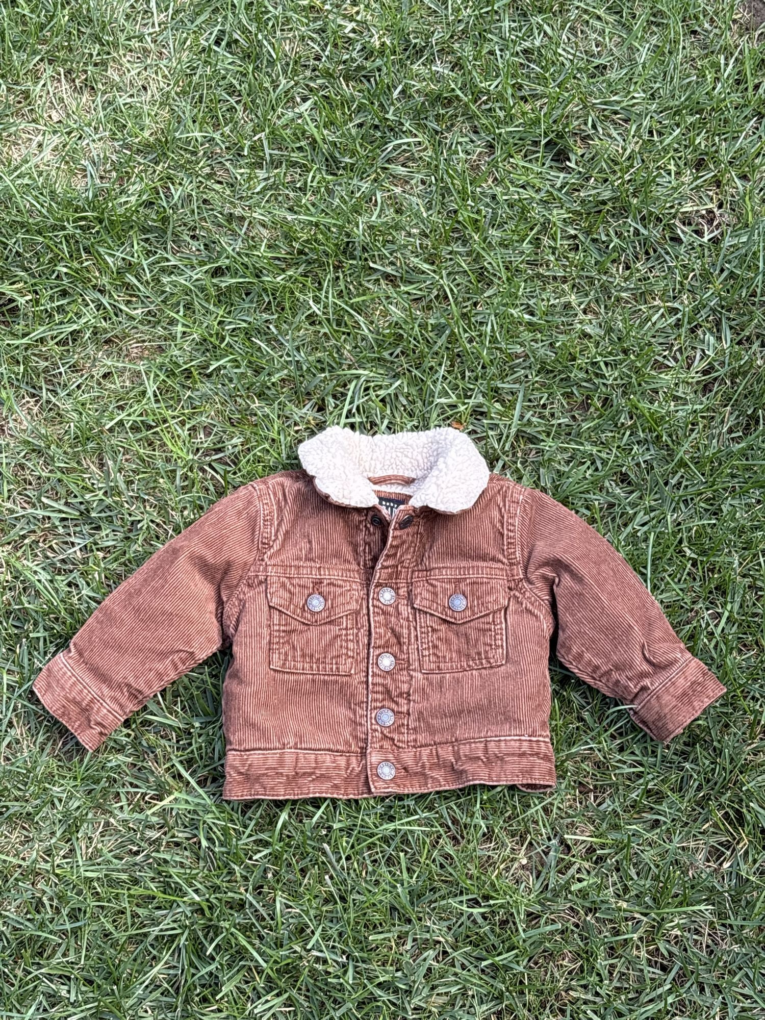 Pre-loved Gap rust corduroy sherpa-collar trucker jacket, kids size 6-12M, front view, laid flat on grass
