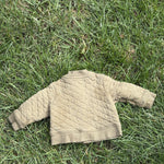 Pre-loved Hanna Andersson khaki quilted snap-front jacket, kids size 6-12M, back view, laid flat on grass