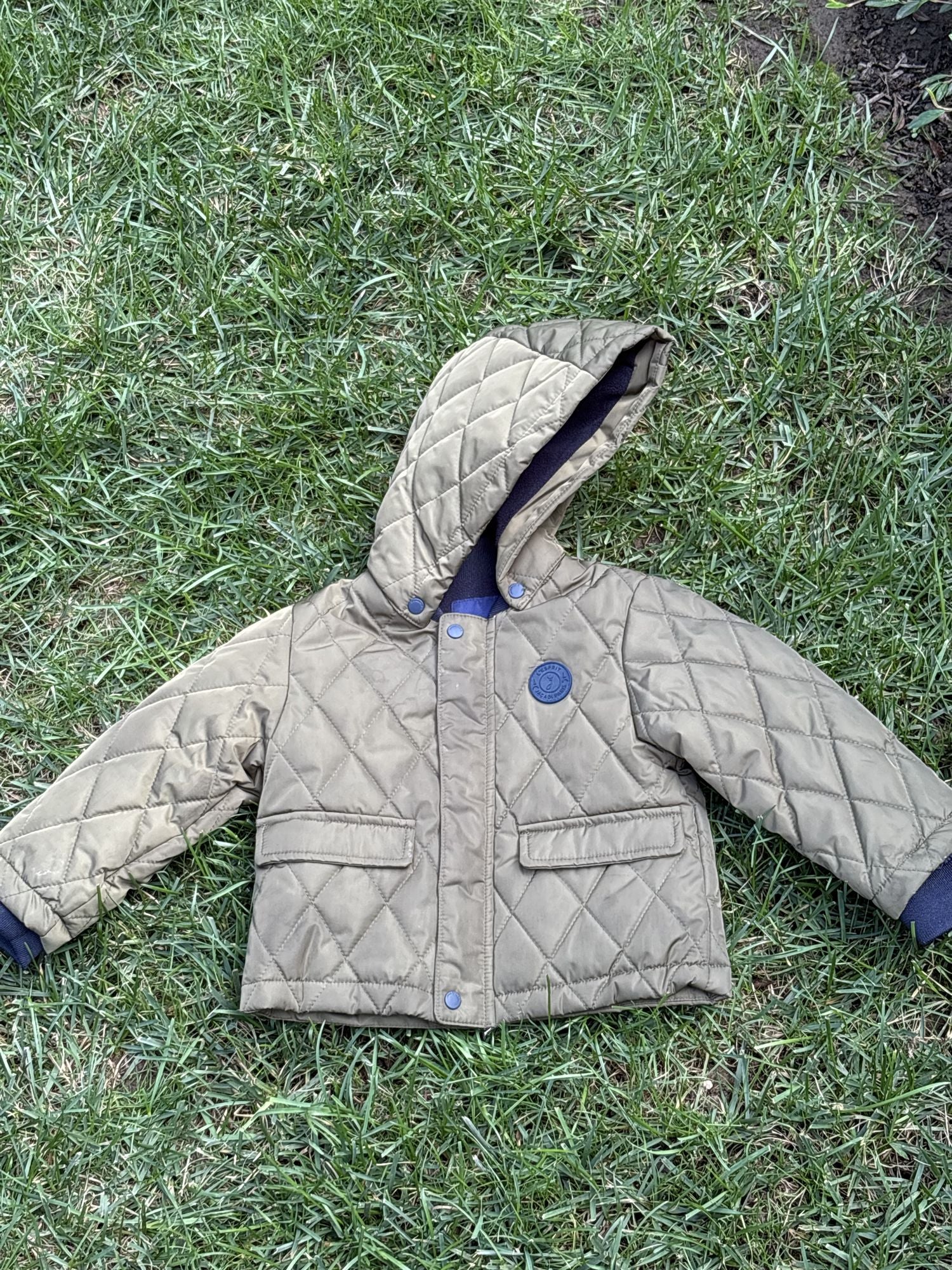 Pre-loved Jacadi olive quilted hooded jacket, kids size 18M, front view, laid flat on grass