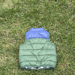 Pre-loved Janie and Jack green and blue colorblock puffer vest, kids size 18-24M, back view, laid flat on grass