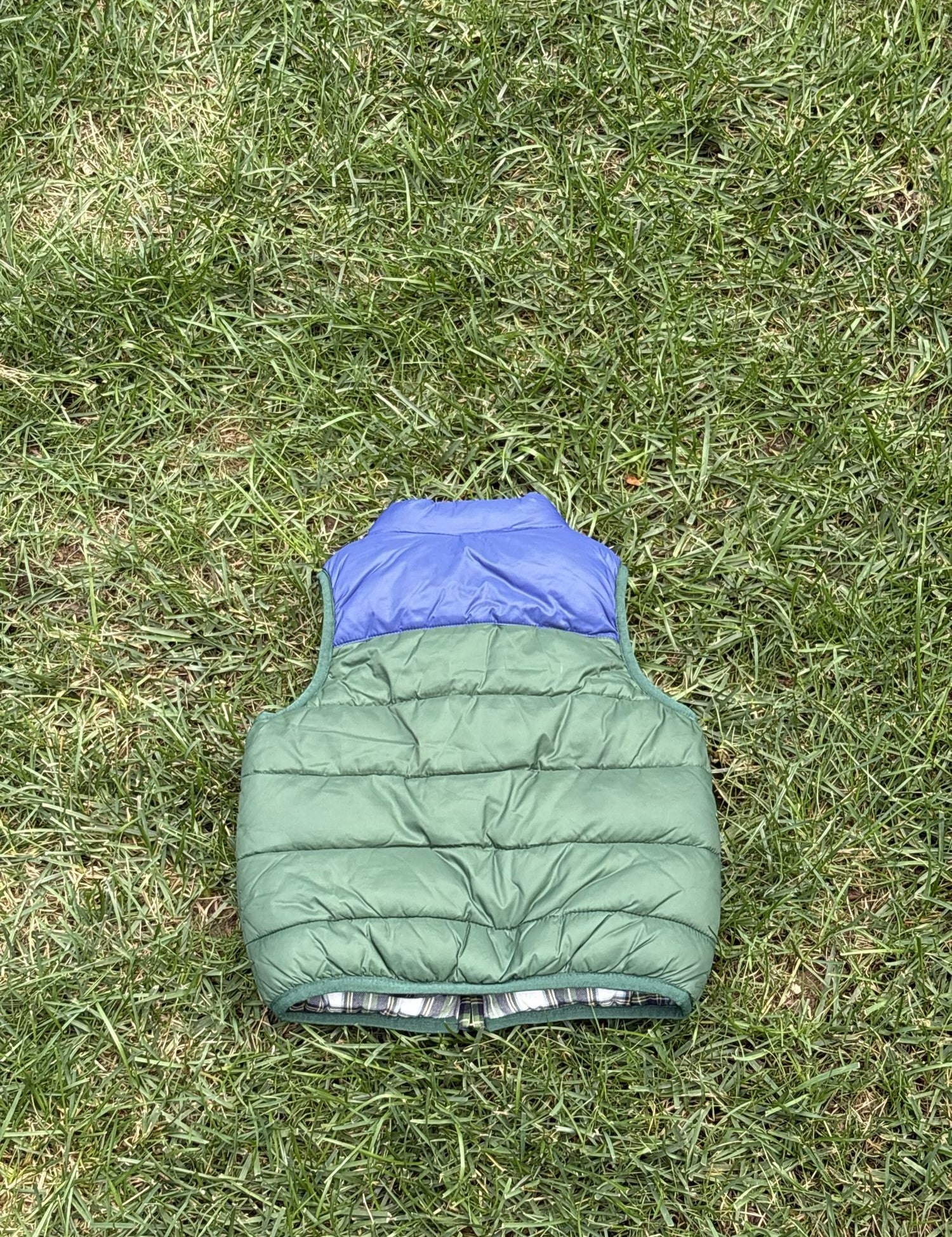 Pre-loved Janie and Jack green and blue colorblock puffer vest, kids size 18-24M, back view, laid flat on grass
