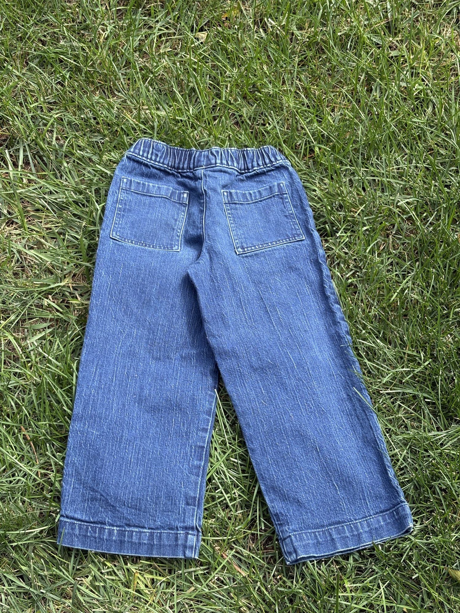 Pre-loved J.Crew wide-leg pull-on jeans, kids size 8, back view, laid flat on grass