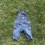 Pre-loved Old Navy denim workwear bib overalls, kids size 3-6M, front view, laid flat on grass