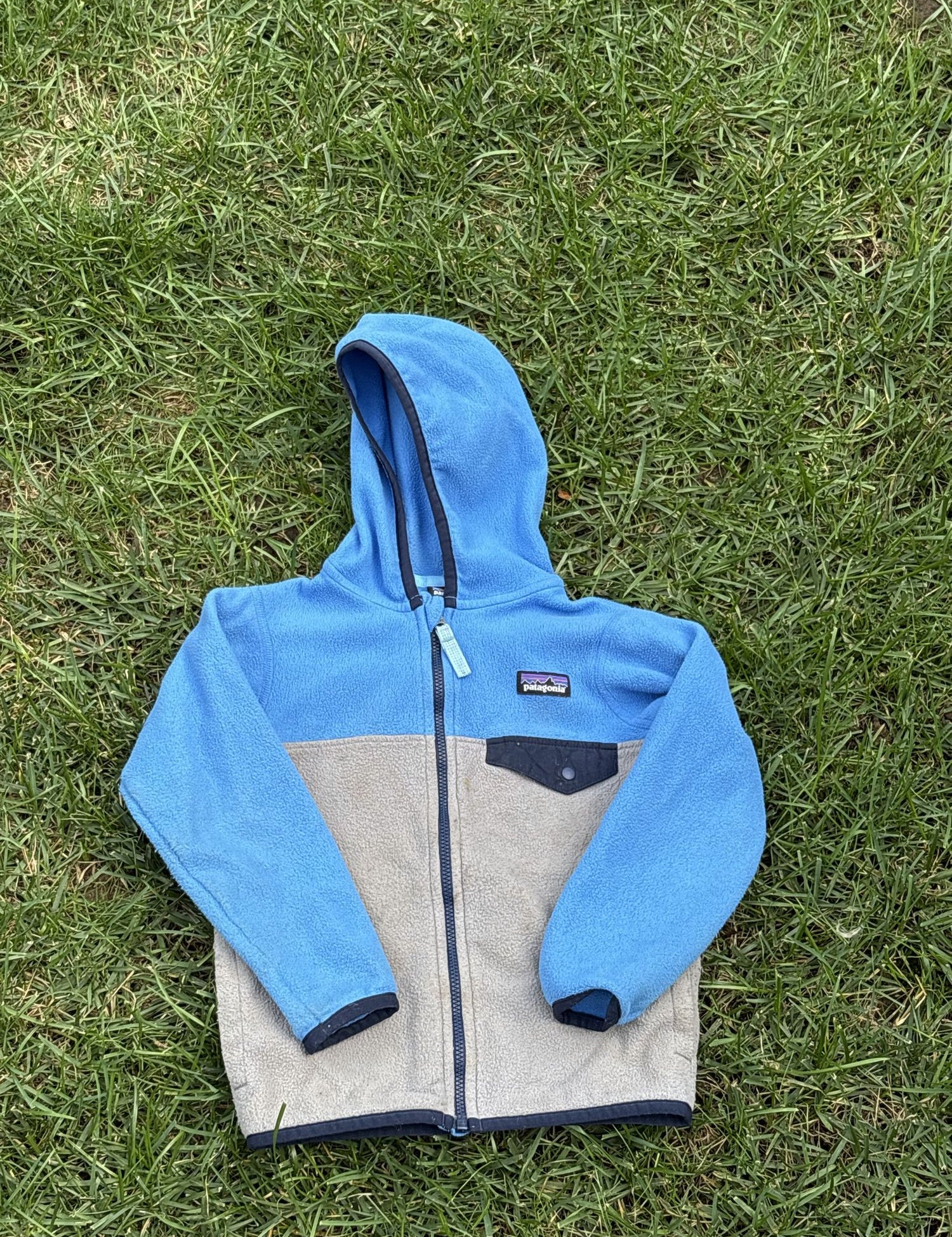 Pre-loved Patagonia blue and gray colorblock hooded fleece jacket, kids size 4T, front view, laid flat on grass