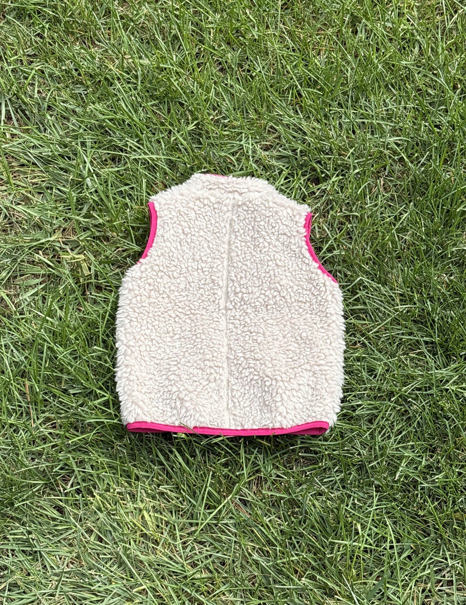Pre-loved Patagonia cream retro-x fleece vest, kids size 12-18M, back view, laid flat on grass