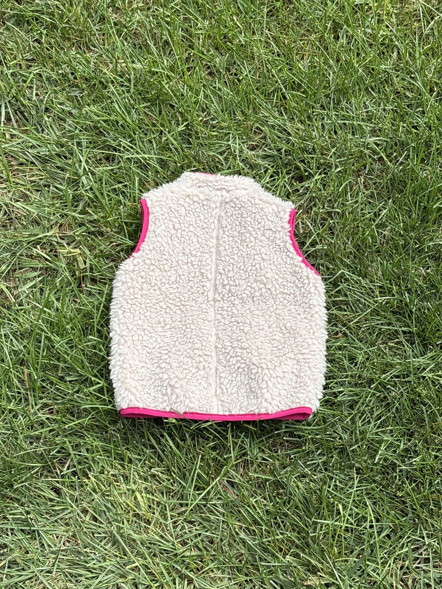 Pre-loved Patagonia cream retro-x fleece vest, kids size 12-18M, back view, laid flat on grass