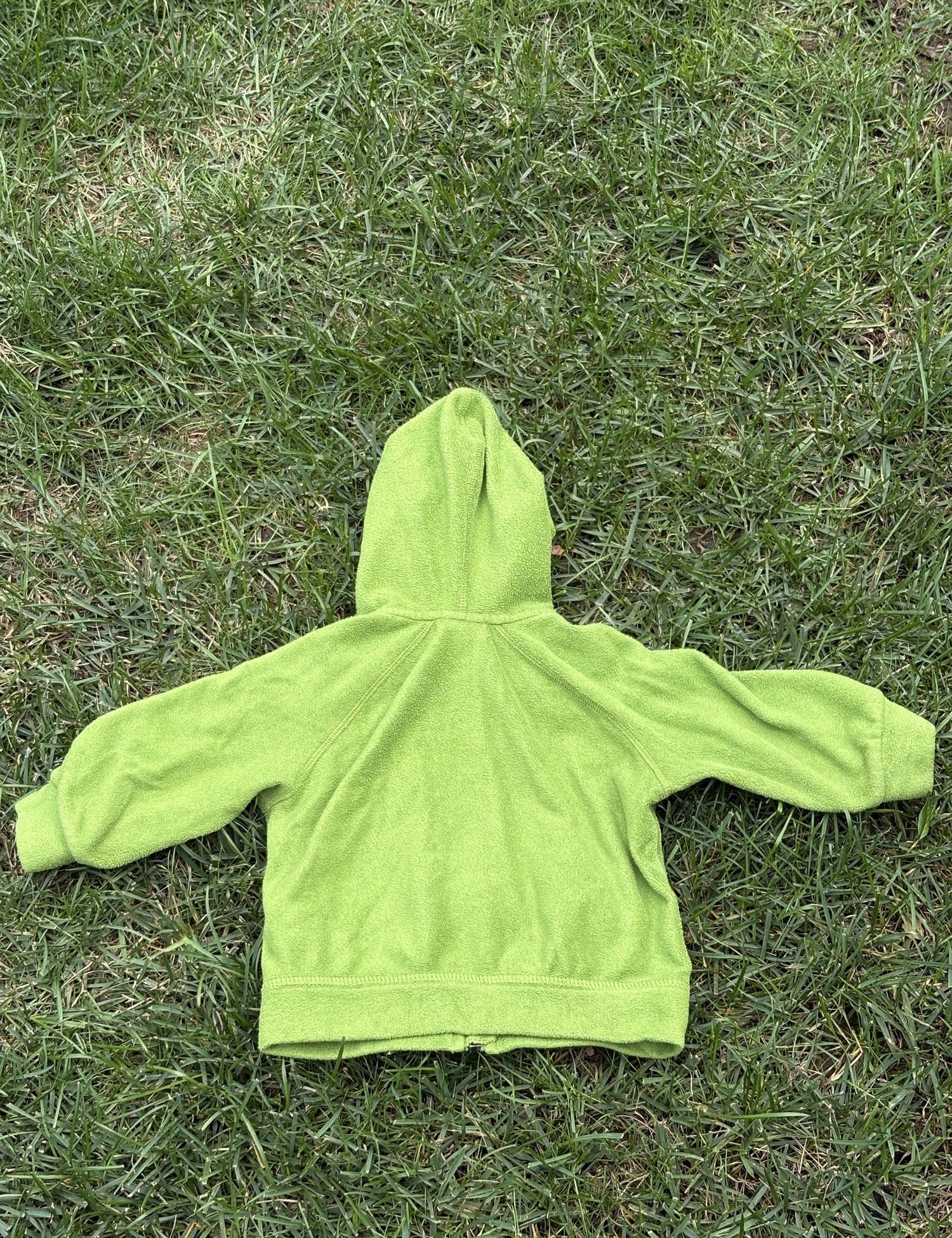 Pre-loved Patagonia green hooded full-zip fleece jacket, kids size 6M, back view, laid flat on grass