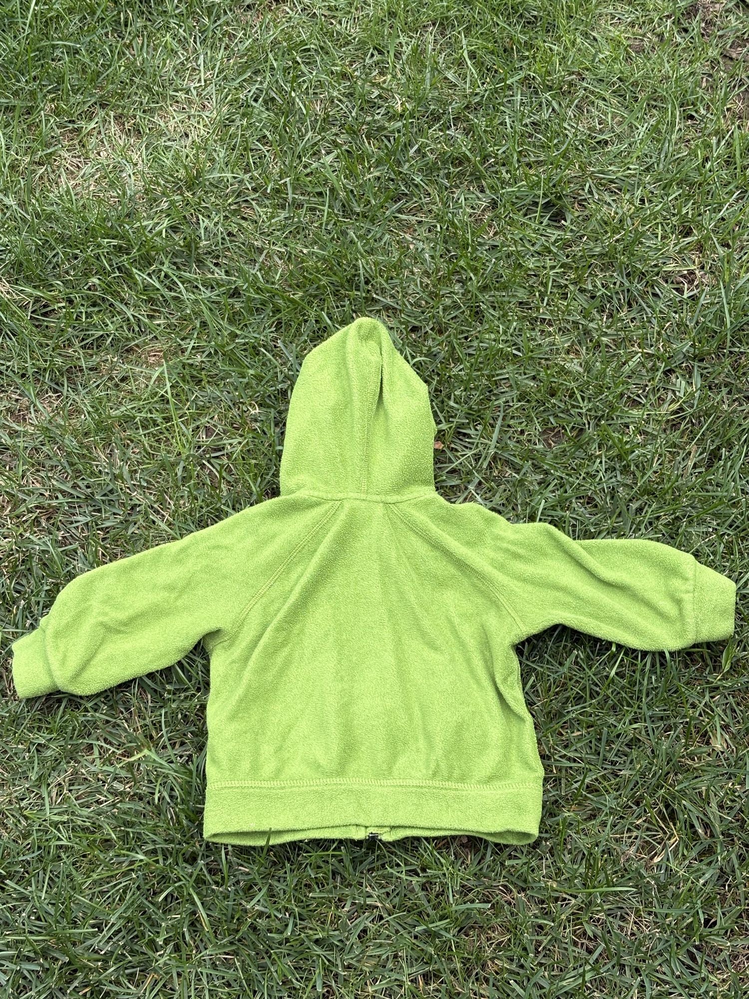 Pre-loved Patagonia green hooded full-zip fleece jacket, kids size 6M, back view, laid flat on grass