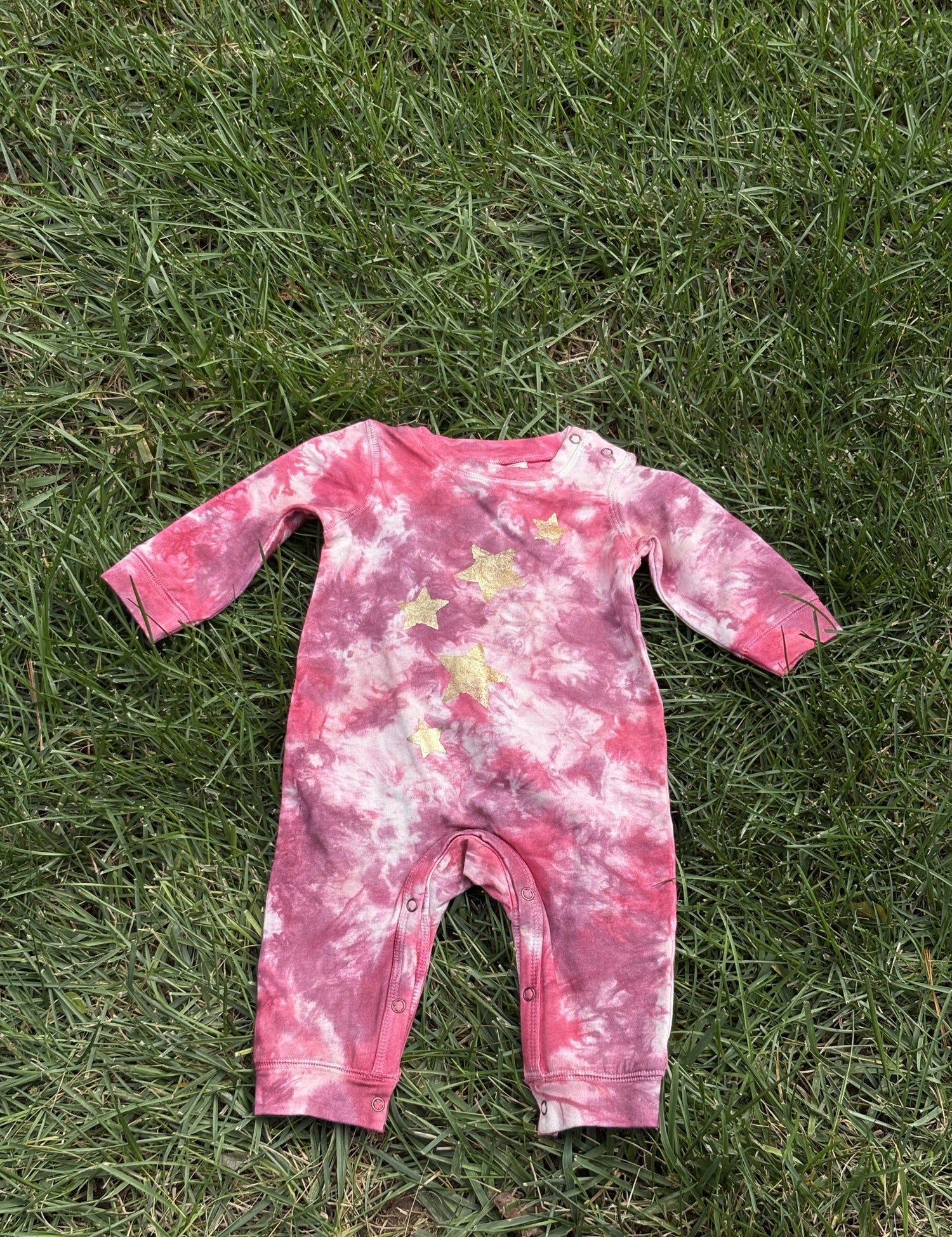 Pre-loved Red Egg & Ginger pink tie-dye gold star romper, kids size 3-6M, front view, laid flat on grass