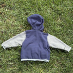 Pre-loved The North Face navy and gray full-zip fleece hoodie, kids size 3-6M, back view, laid flat on grass