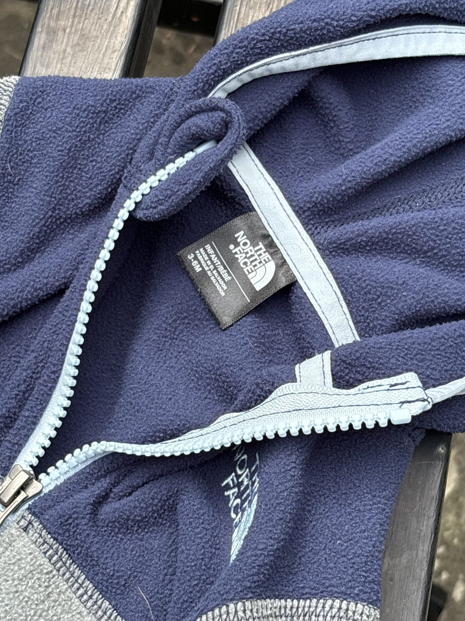 Pre-loved The North Face navy and gray full-zip fleece hoodie, kids size 3-6M, brand and size label close-up
