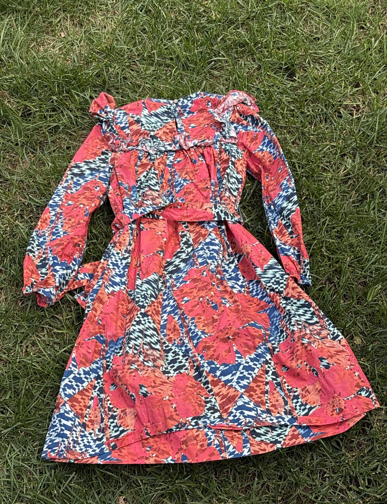 Pre-loved Ulla Johnson coral and blue botanical print dress, kids size 6, back view, laid flat on grass