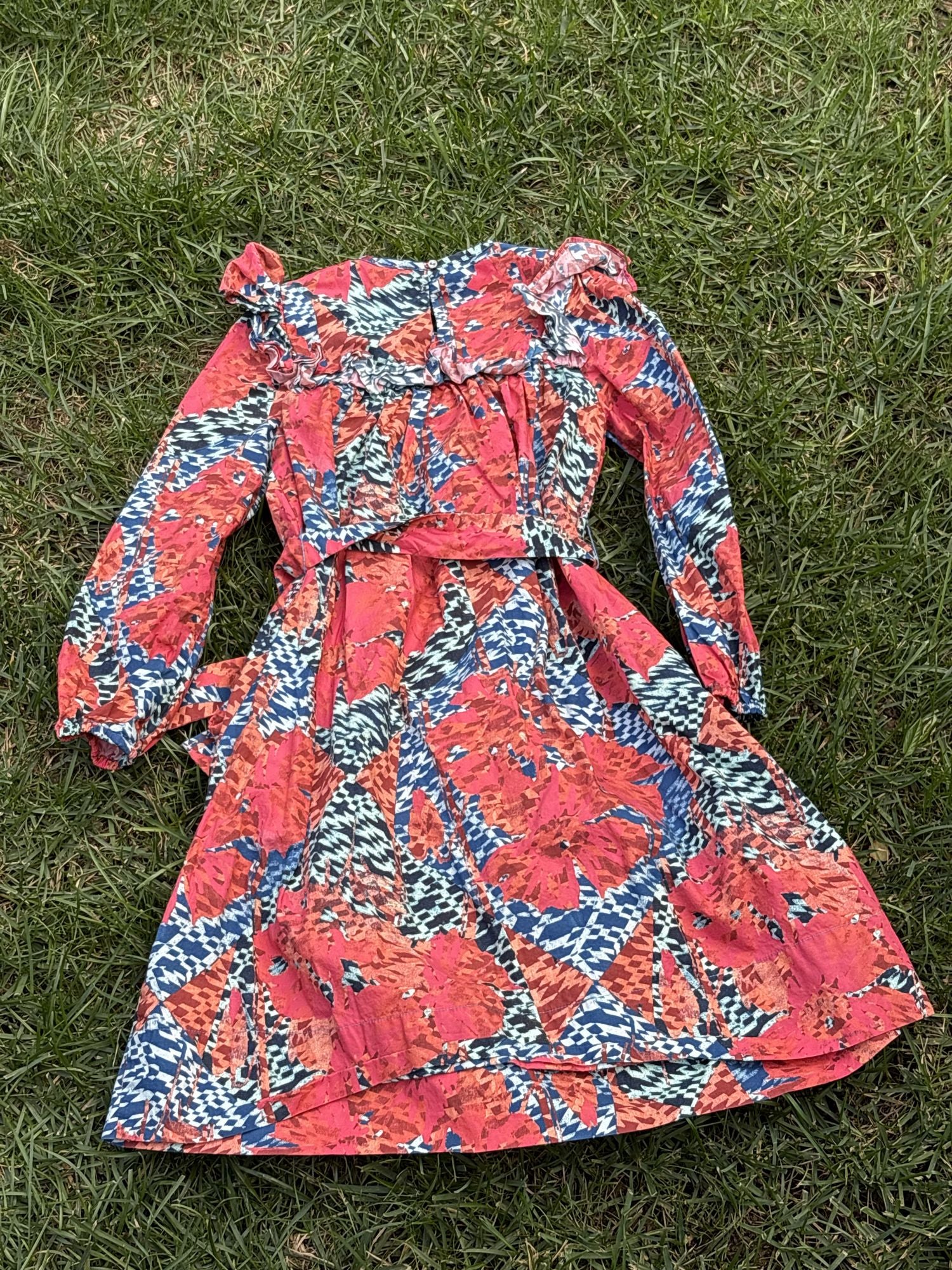 Pre-loved Ulla Johnson coral and blue botanical print dress, kids size 6, back view, laid flat on grass