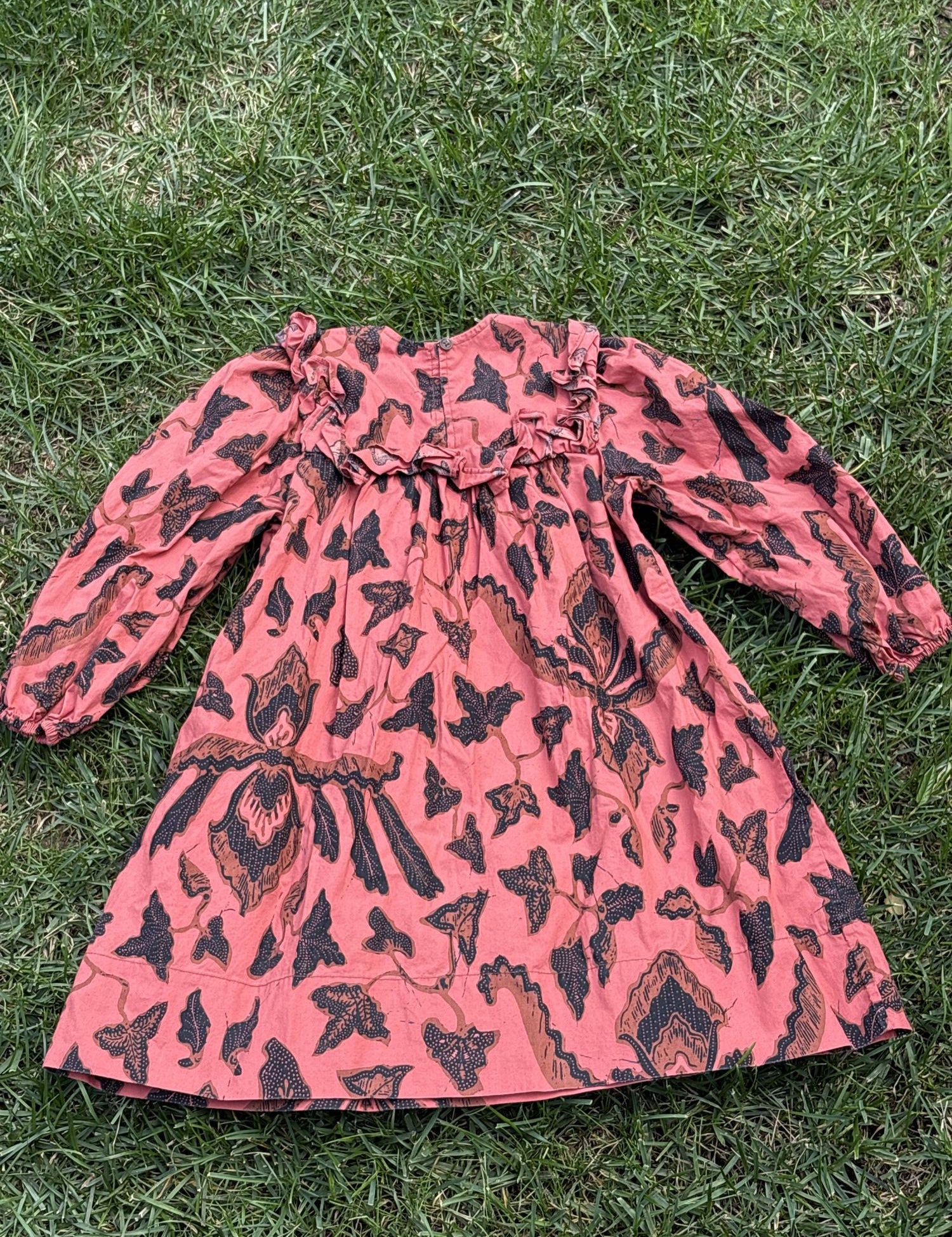 Pre-loved Ulla Johnson coral botanical print long-sleeve dress, kids size 4, back view, laid flat on grass