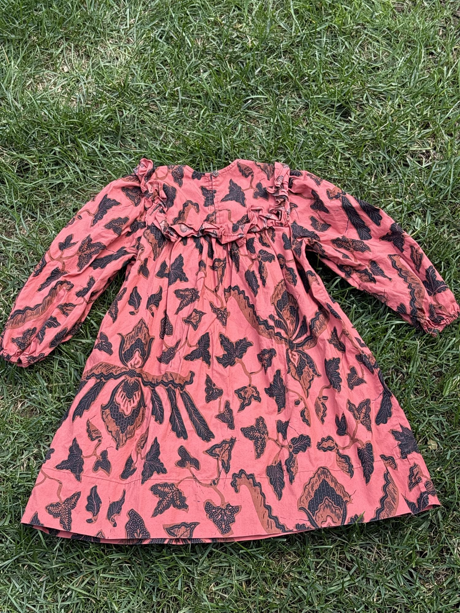 Pre-loved Ulla Johnson coral botanical print long-sleeve dress, kids size 4, back view, laid flat on grass