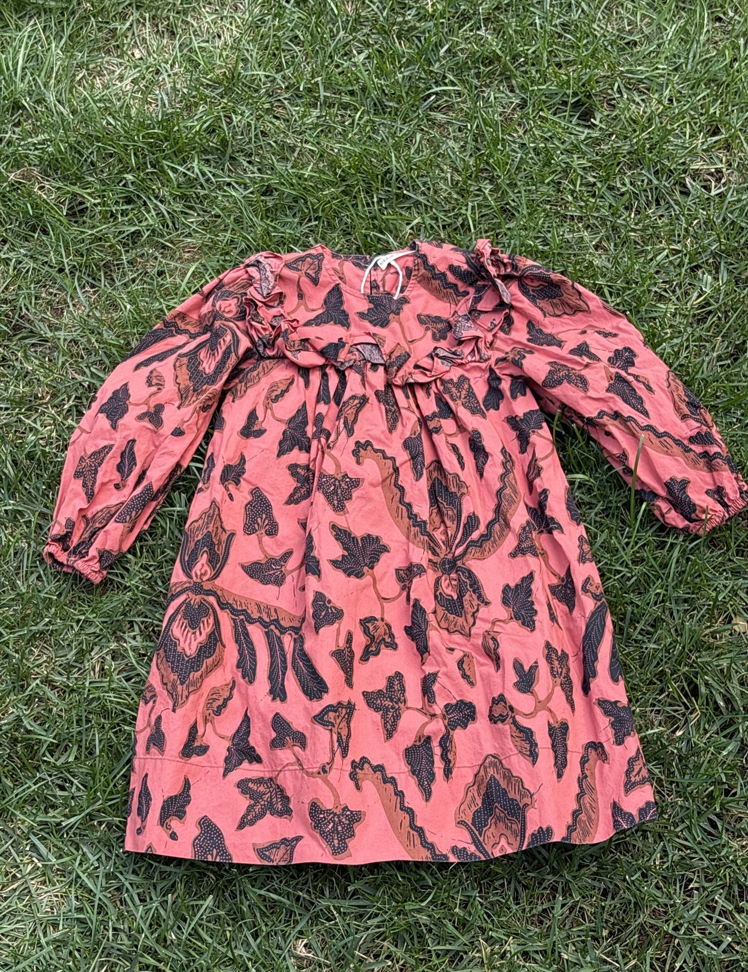 Pre-loved Ulla Johnson coral botanical print long-sleeve dress, kids size 4, front view, laid flat on grass