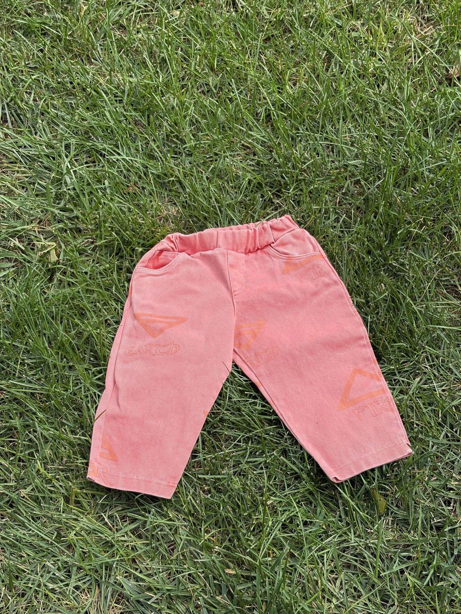 Pre-loved Unbranded coral star print pull-on pants, kids size 3T, front view, laid flat on grass