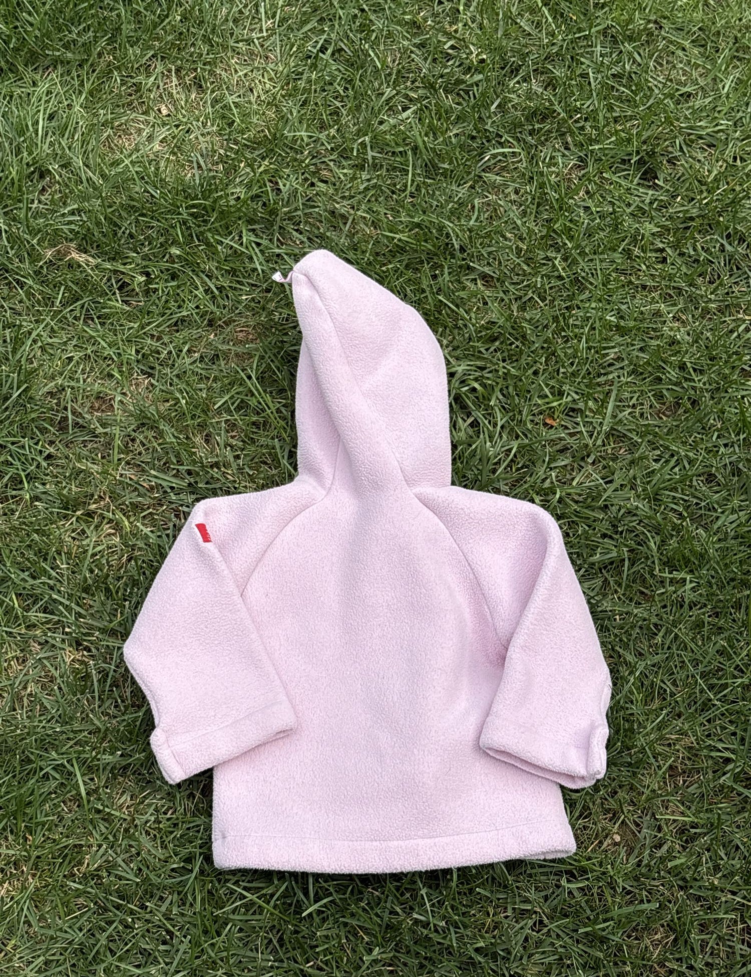 Pre-loved Widgeon pink polartec fleece hooded jacket, kids size 9M, back view, laid flat on grass