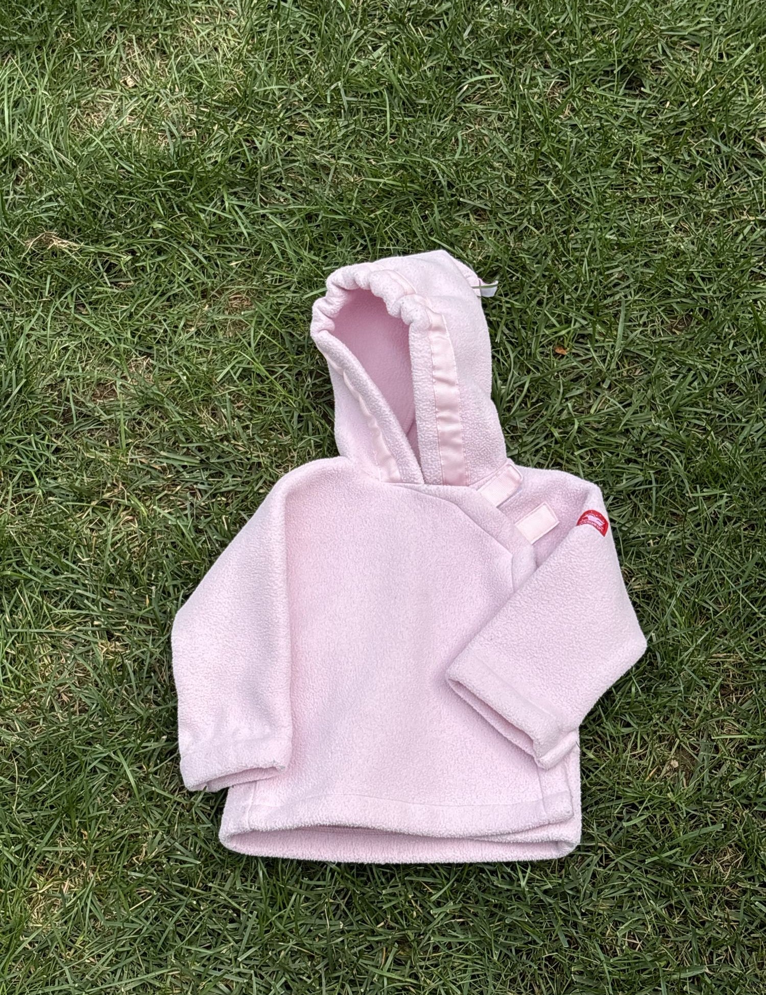 Pre-loved Widgeon pink polartec fleece hooded jacket, kids size 9M, front view, laid flat on grass