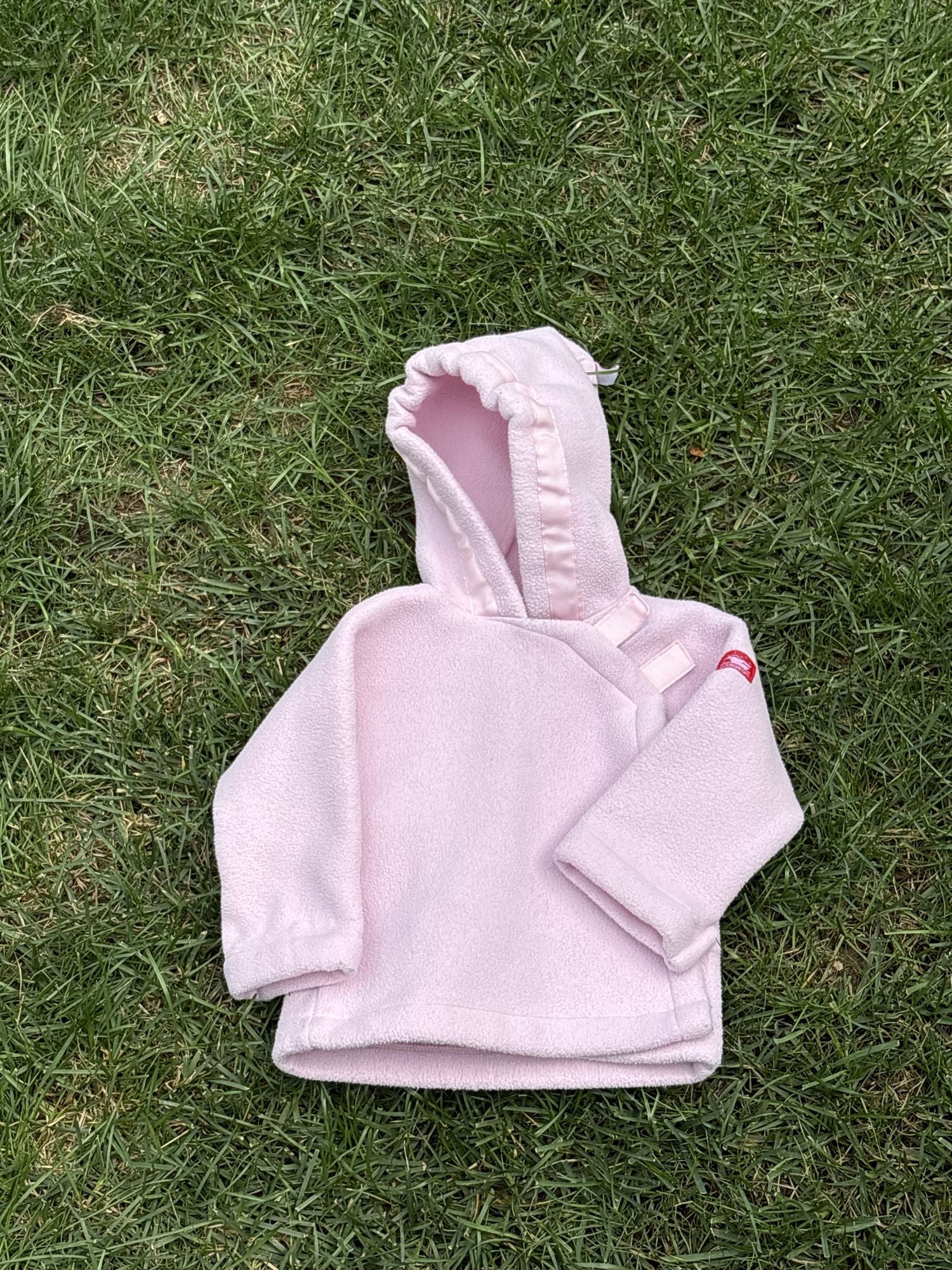 Pre-loved Widgeon pink polartec fleece hooded jacket, kids size 9M, front view, laid flat on grass